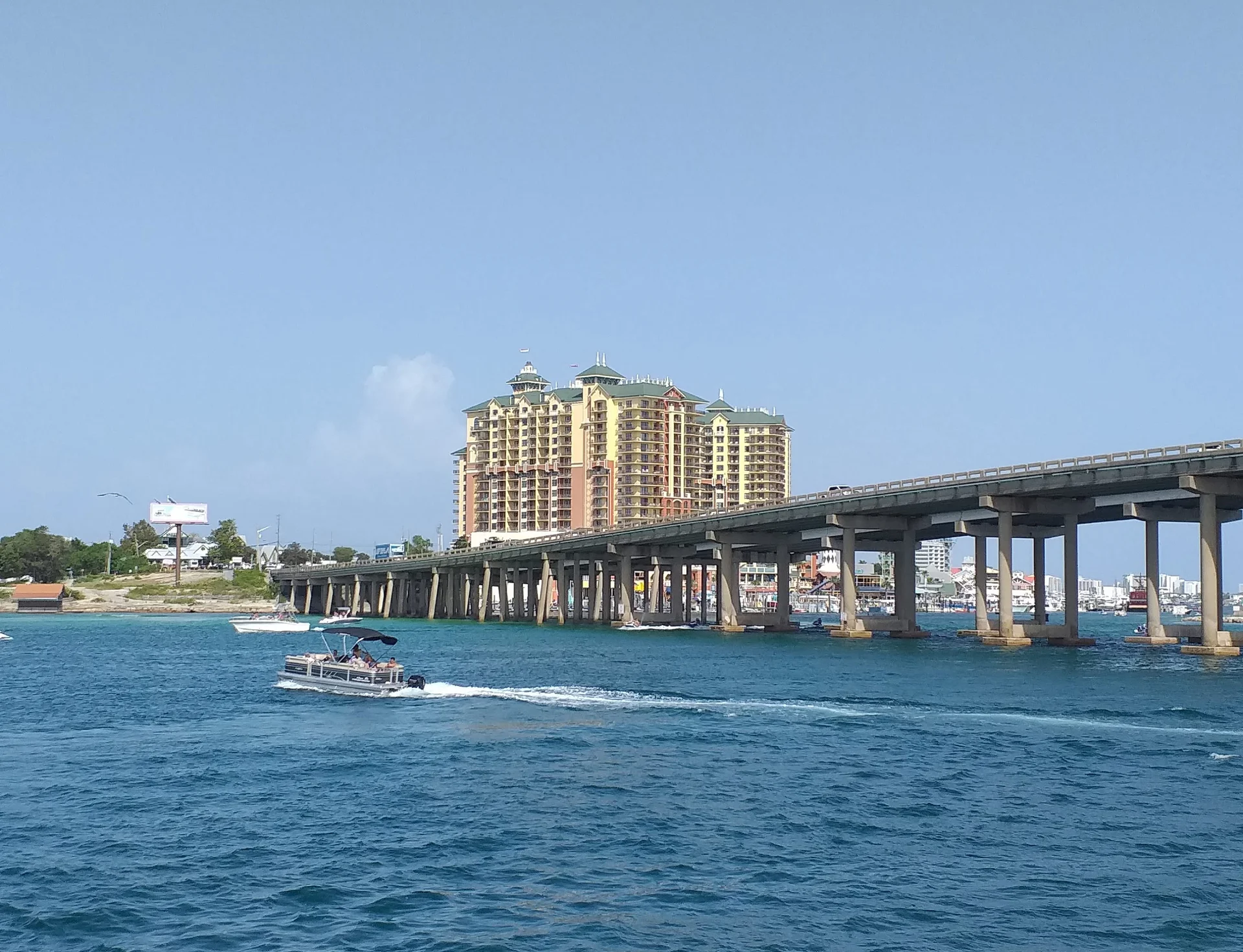 Boats passing beneath the road bridge at Destin, Florida, with harbourfront condominium towers behind